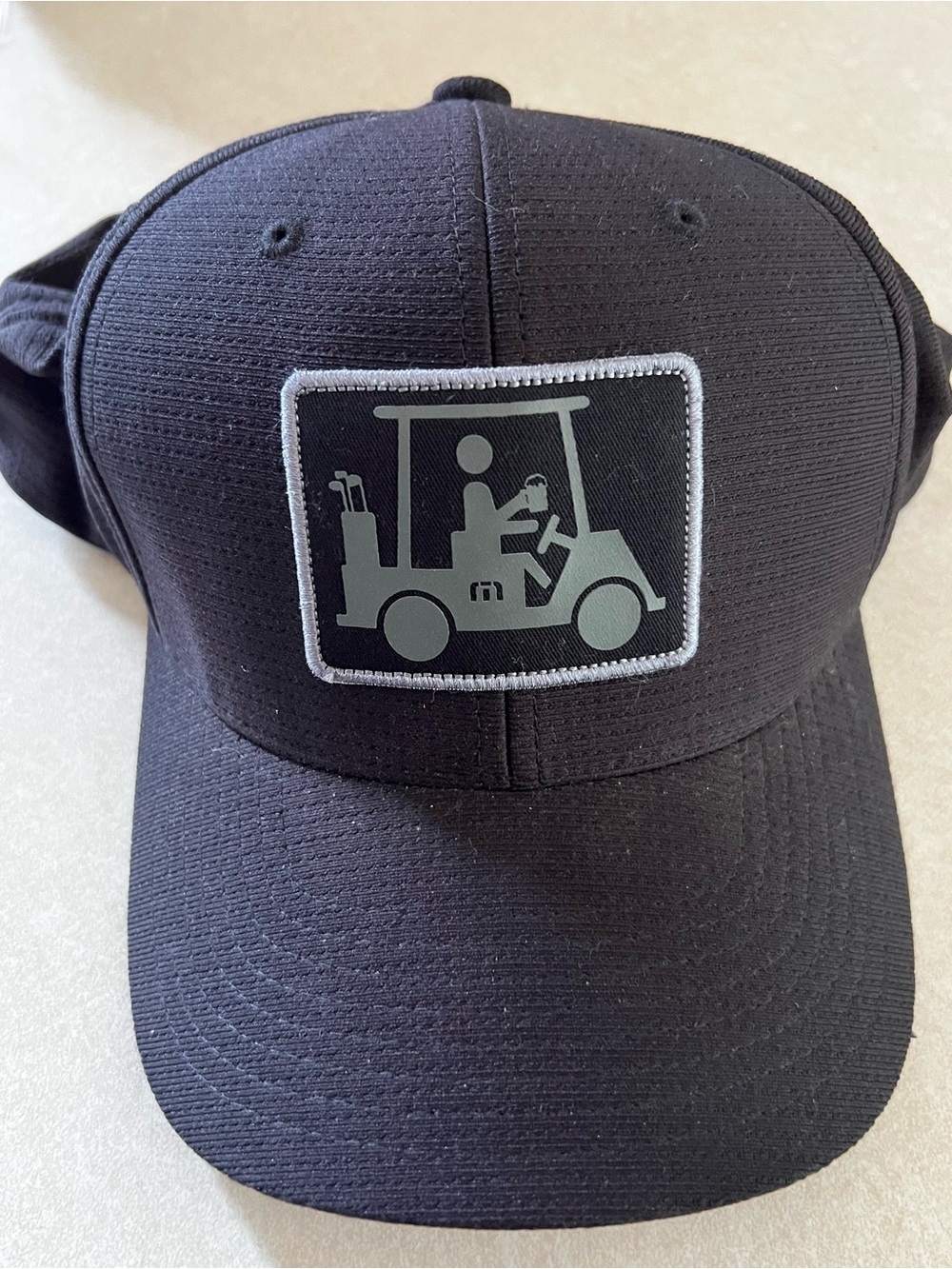 Travis Matthew’s black Golf Cart Patch Baseball Cap